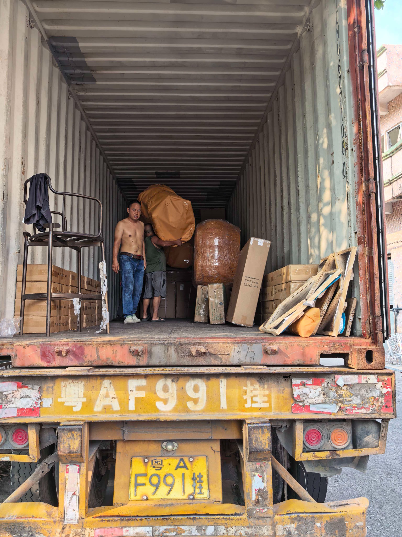 Furniture and packaged cargo being loaded into a container in China